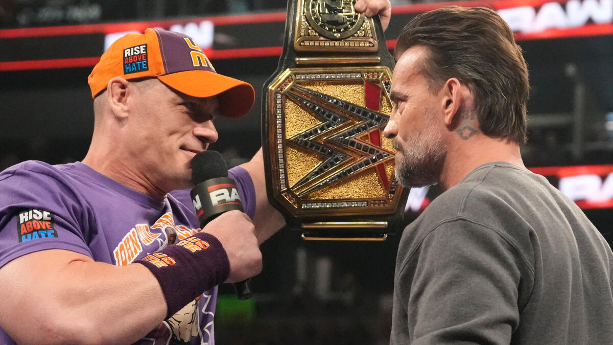 John Cena holding Undisputed WWE Championship belt at CM Punk's face
